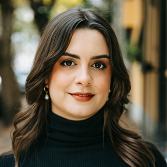 Bianca Mulet headshot. Bianca has long dark hair and is smiling slightly. Bianca is wearing a black turtle-neck and pearl drop-earrings.